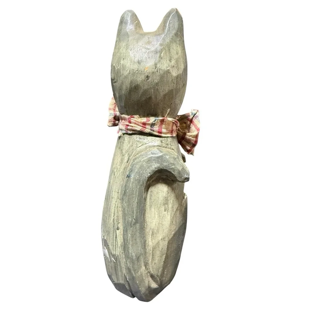 hand-carved wooden cat figurine with a painted finish and a plaid cloth scarf.